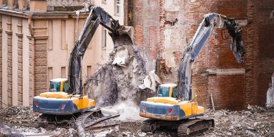 Building of the former hotel demolition for new construction, using a two special hydraulic excavator-destroyer. Complete mechanized demolition of a building. Reinforced concrete structures.